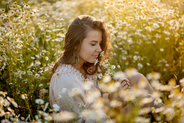 Beautiful girl with long hair in a camomile field