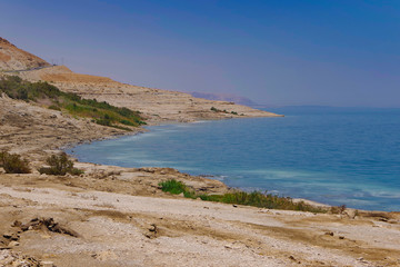 Fototapeta na wymiar The coast of the dead sea against the backdrop of the mountains and the blue sky. 