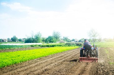 Obraz premium A farmer on a tractor cultivates a field before a new planting. Loosening the surface, cultivating land for further planting. Soil milling, crumbling and mixing. Agroindustry, farming. Growing food