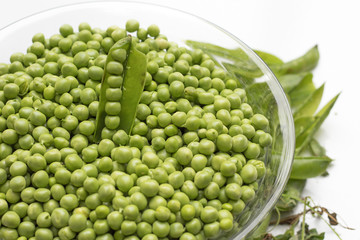 Fresh green peas in a glass bowl isolated on white background. 