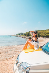 Obraz premium woman sitting at car hood drinking coffee enjoying view of the sea