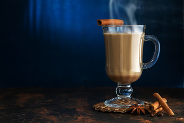 Masala tea with cinnamon and badian on a clay table. A glass of Masala tea on a blue background.