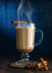 Masala tea with cinnamon and badian on a clay table. A glass of Masala tea on a blue background.