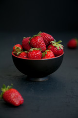 strawberries in a bowl on a black background