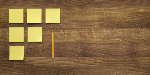 Wooden table background with sticky notes and a pencil