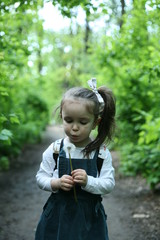 Child alone in the forest.Happy child. Happy little girl. A child in the forest holding a dandelion in his hands.The child goes to school. A children has a backpack on his shoulders.