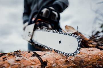 Close up professional chainsaw cuts firewoods