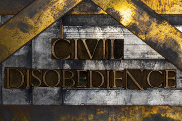 Photo of real authentic typeset letters forming Civil Disobedience text on vintage textured grunge silver and gold background