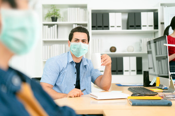 Shot of a businessman holding coffee cup to be drink while still wearing surgical mask, Concept of people unfamiliarity with new normal life while coronavirus or covid-19 pandemic situation.