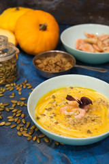 Autumn food - pumpkin soup with cream, shrimps and seeds in bowls on table. Served for dinner. View from above