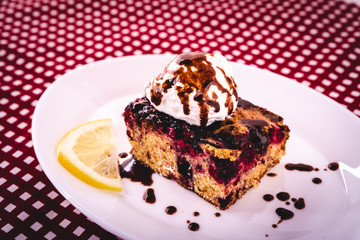 Homemade cake with forest fruit served on a plate with a glass of refreshing lemonade with lemon slice