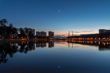 The conjunction of the Moon and Venus in the evening sunset sky over a lake in the very center of Zelenograd
