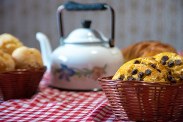 arrangement with breads, sweets and teapot on a red and white towel