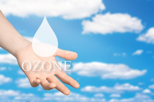 Drops ozone of water in human hands on blue sky background