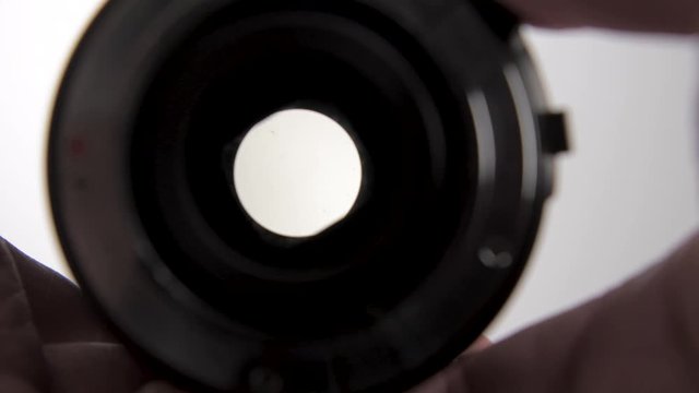 View of the movement of a diaphragm of an old manual camera lens opening and closing the aperture. White Background