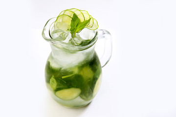 Lemonade made from cucumber slices and green Basil in a tall glass jug on a white background. An isolated object. Copy space.