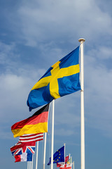 Flags from Denmark, Norway, Sweden, Germany and United Kingdom waving from flagpoles together.