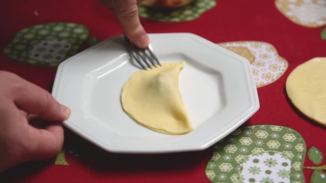 Selando uma massa de pastel com um garfo. Preparo de um lanche brasileiro. Pastel.