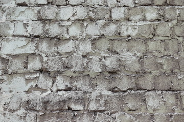 a weathered wall of cemented grey square bricks 