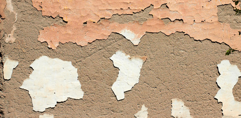 old wall with peeling stucco with flakes of paint