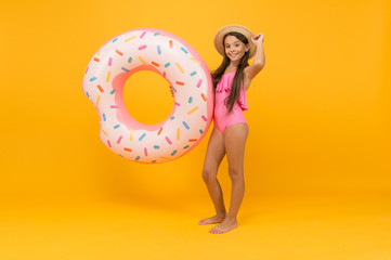 Enjoying suntan and vacation. pool party. carefree kid with rubber ring. summer beach activity. happy childhood. small girl wear straw hat and swimsuit. smiling child. holiday and vacation