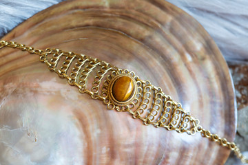 Brass wire bracelet with tiger eye mineral stone on natural shell background