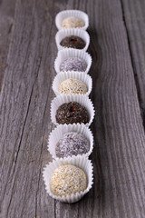 Raw energy bites balls prepared with natural ingredients on old rustic wooden background