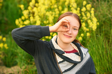 Naklejka premium Outdoor portrait of young teen girl looking through fingers