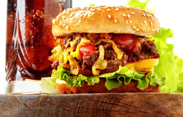 Closeup of tasty homemade hamburger with coca cola salad, beef, onions and peppers on a wooden...