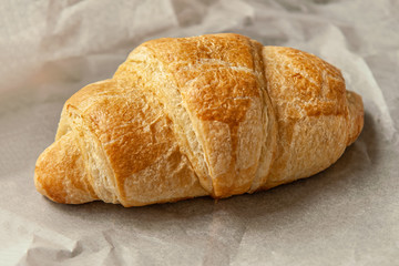 freshly baked flavorful crispy croissant on white parchment close up