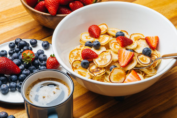 Tiny pancakes for breakfast. Pancakes with strawberries and blueberries cooked in the morning for breakfast in the home kitchen. Food Background.
