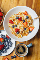 Tiny pancakes for breakfast. Pancakes with strawberries and blueberries cooked in the morning for breakfast in the home kitchen. Food Background.