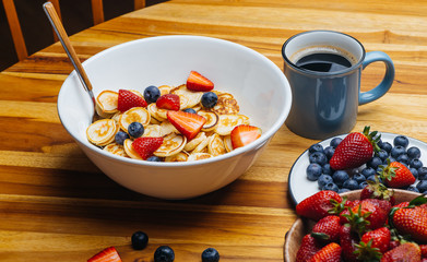Tiny pancakes for breakfast. Pancakes with strawberries and blueberries cooked in the morning for breakfast in the home kitchen. Food Background.