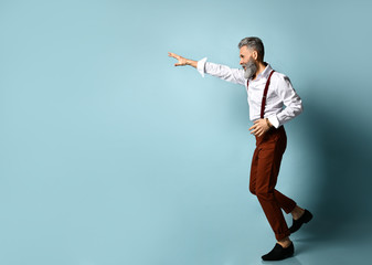 Aged man in white shirt, brown pants and suspenders, black loafers. He runs looking back, raised his hand up, blue background
