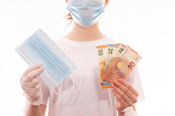girl in a medical mask in hands holds a medical mask and money