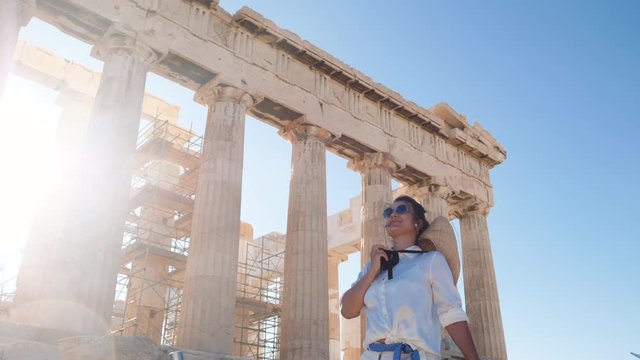 Young Woman visiting Parthenon, Acropolis of Athens, Greece. Large hat, fashion white dress, sunglasses, vintage camera.