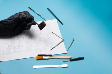 Top view, technician hands repairing SD card with tools on blue background. data storage concept....