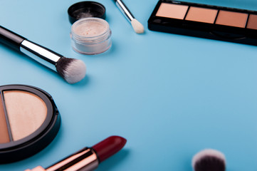 Cosmetic palette and face shadow with brushes lies on a blue background