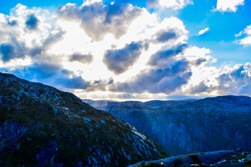 Gorgeous sunbeams pass through the clouds illuminating the mountain range where the path to Kjeragbolten lies. Norway.