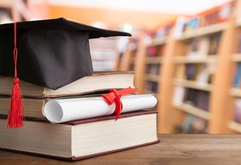 Graduation hat on stack of books and diploma