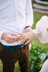 Wedding at an old winery villa in Tuscany, Italy. The groom puts a wedding ring on the brides finger, close-up of hands.