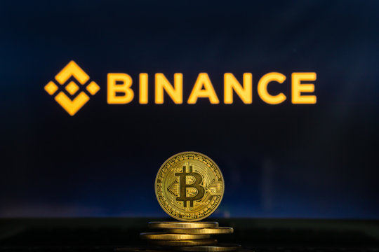 Bitcoin on a stack of coins with Binance logo on a laptop screen. Cryptocurrency and blockchain adoption getting mainstream. Slovenia - 02 24 2019