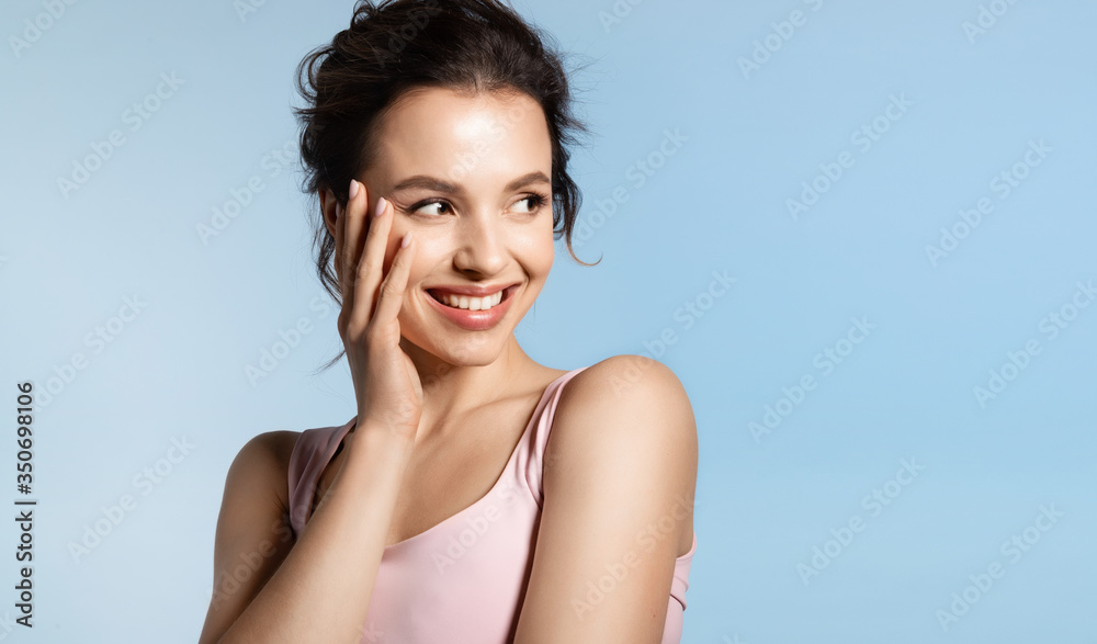 Wall mural Young woman with bare shoulder and shiny glowing perfect face skin laughing timid. 