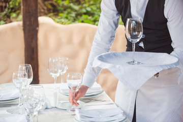 the waiter works in a restaurant on the summer terrace.