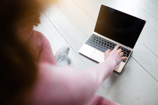 Close-up of a laptop screen with a black screen for inserting an image and a female hand reaching for the keyboard.