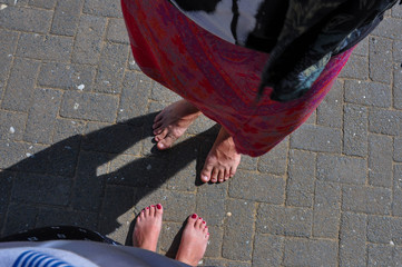 Male and female bare feet on the asphalting ground at the daylight before entering the Buddhist temple.