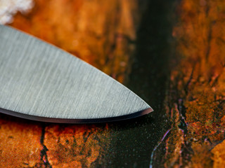 Cutting edge of folding knife with tip on background closeup