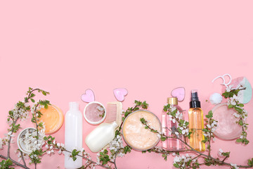 Spa ingredients, a set of creams for skin and body care on a pink background with branches of blooming cherry. Shopping concept and modern woman, sale, top view, selective focus