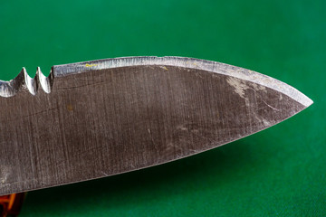 Cutting edge of blunt knife with damaged blade on green background close up