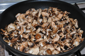 Raw fresh brown champignons cut in small pieces in a pan before frying.